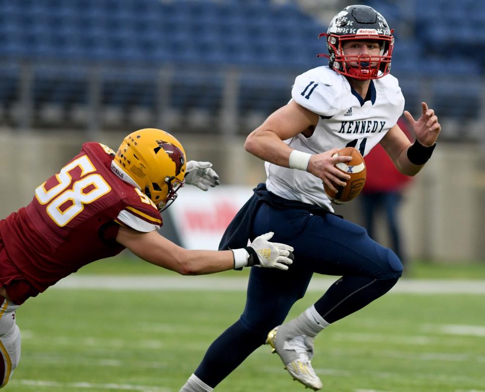 Warren JFK's quarterback Caleb Hadley looks for a receiver under pressure from New Bremen's Carter Elking in the first quarter of the OHSAA Division VII state final at Tom Benson Hall of Fame Stadium. Saturday, Dec. 3, 2022.