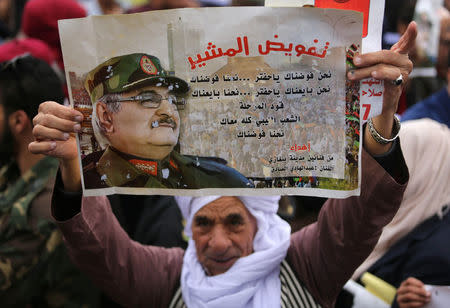 A supporter of Eastern Libyan military commander Khalifa Haftar holds a poster of Haftar during a rally demanding him to take over, in Benghazi, Libya, December 17, 2017. REUTERS/Esam Omran Al-Fetori