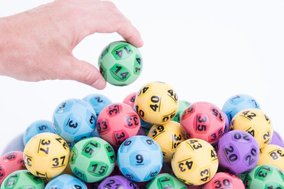 Man's hand draws out lottery ball from pile.