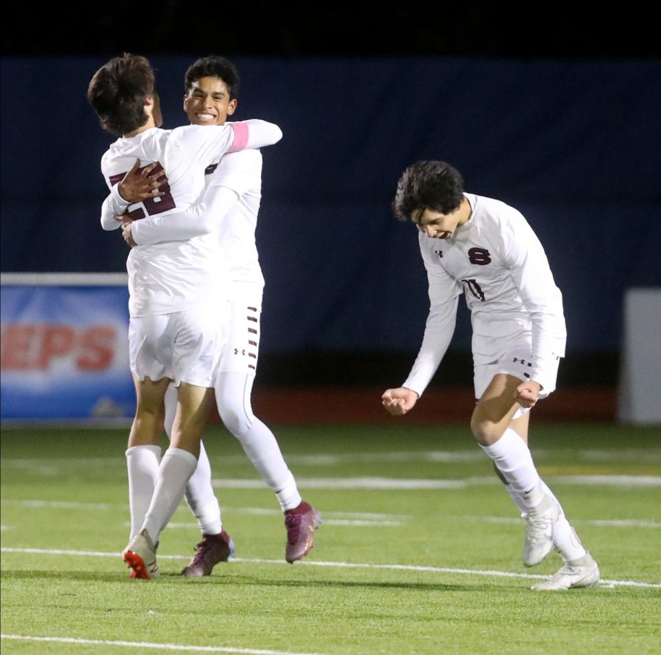 Nicolas Galeano, (center), is congratulated after scoring ScarsdaleÕs first goal against McQuaid Jesuit in the New York State Class AA Soccer Championship at Middletown High School Nov. 13, 2022. Scarsdale defeated McQuad Jesuit 2-0.