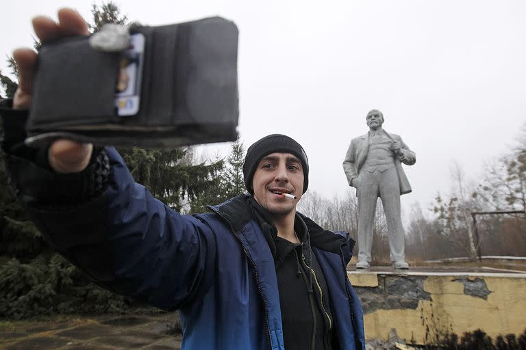 En Pripyat, Ucrania, un hombre se toma un selfie con una estatua del líder soviético Vladimir Lenin en la zona de exclusión de Chernobyl durante un recorrido turístico