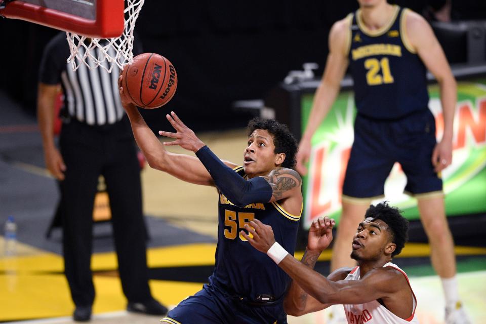 Michigan guard Eli Brooks (55) goes to the basket past Maryland guard Hakim Hart, right, during the first half of an NCAA college basketball game Thursday, Dec. 31, 2020, in College Park, Md.