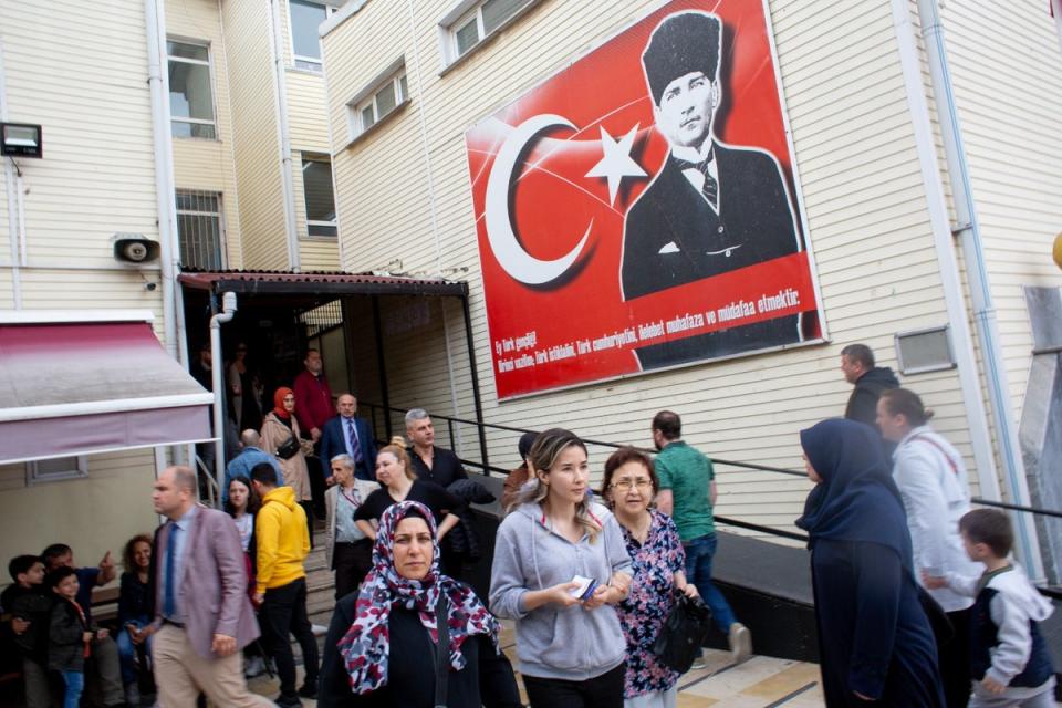 Voters emerge from a polling station in Istanbul beneath a portrait of Mustafa Kemal Ataturk, founder of modern Turkey, in the second round of presidential elections. (Yusuf Sayman/For The Independent)