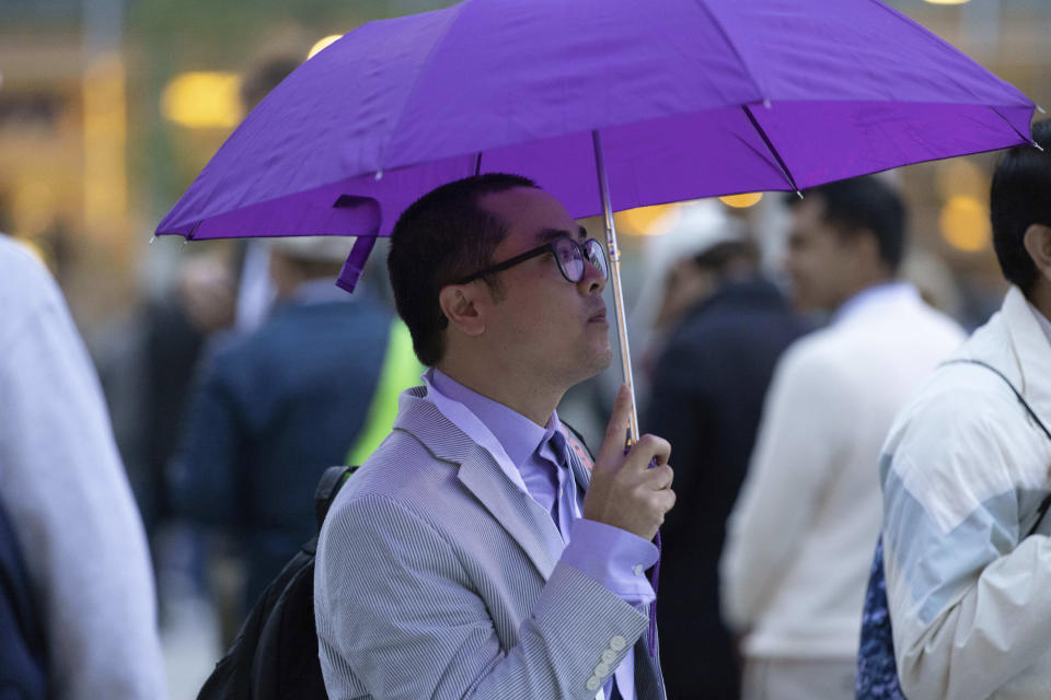 Van Hoan of Dallas shields himself from a light rain while waiting in line to enter the Berkshire Hathaway annual meeting on Saturday, May 6, 2023, in Omaha, Neb. (AP Photo/Rebecca S. Gratz)