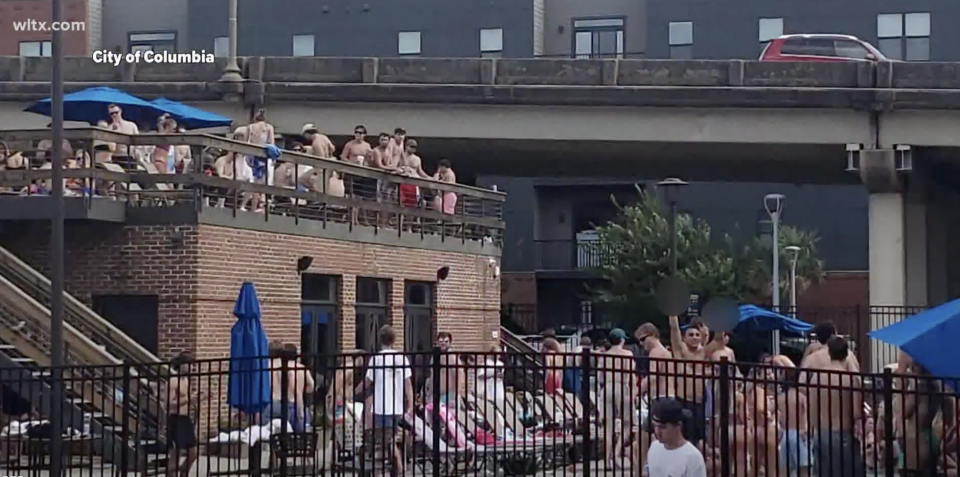 Pictured is a group of partygoers on a roof and surrounding a pool at a Columbia apartment complex. 