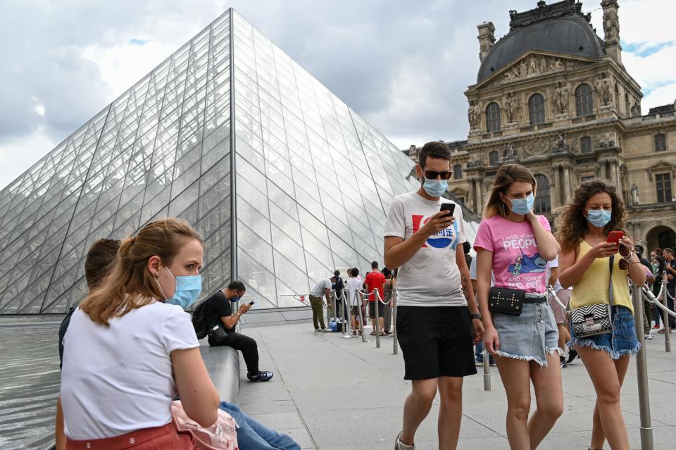 Tourists wearing protective face masks walk past the Louvre Pyramid (Pyramide du Louvre) designed by Ieoh Ming Pei, at the Cour Napoleon, in Paris, on August 15, 2020. (Photo by BERTRAND GUAY / AFP) / RESTRICTED TO EDITORIAL USE - MANDATORY MENTION OF THE ARTIST UPON PUBLICATION - TO ILLUSTRATE THE EVENT AS SPECIFIED IN THE CAPTION (Photo by BERTRAND GUAY/AFP via Getty Images)