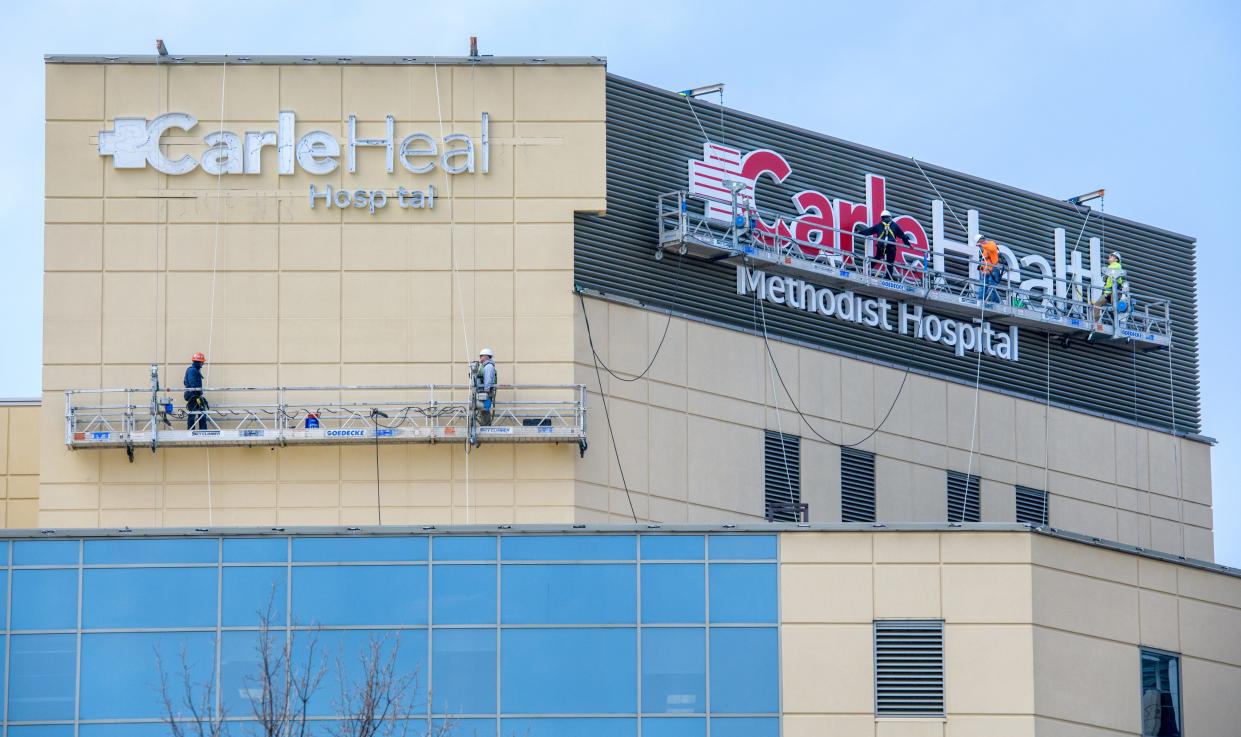 Giant Carle Health signs go up on the side of Methodist Hospital on Tuesday, April 4, 2023, in Peoria.