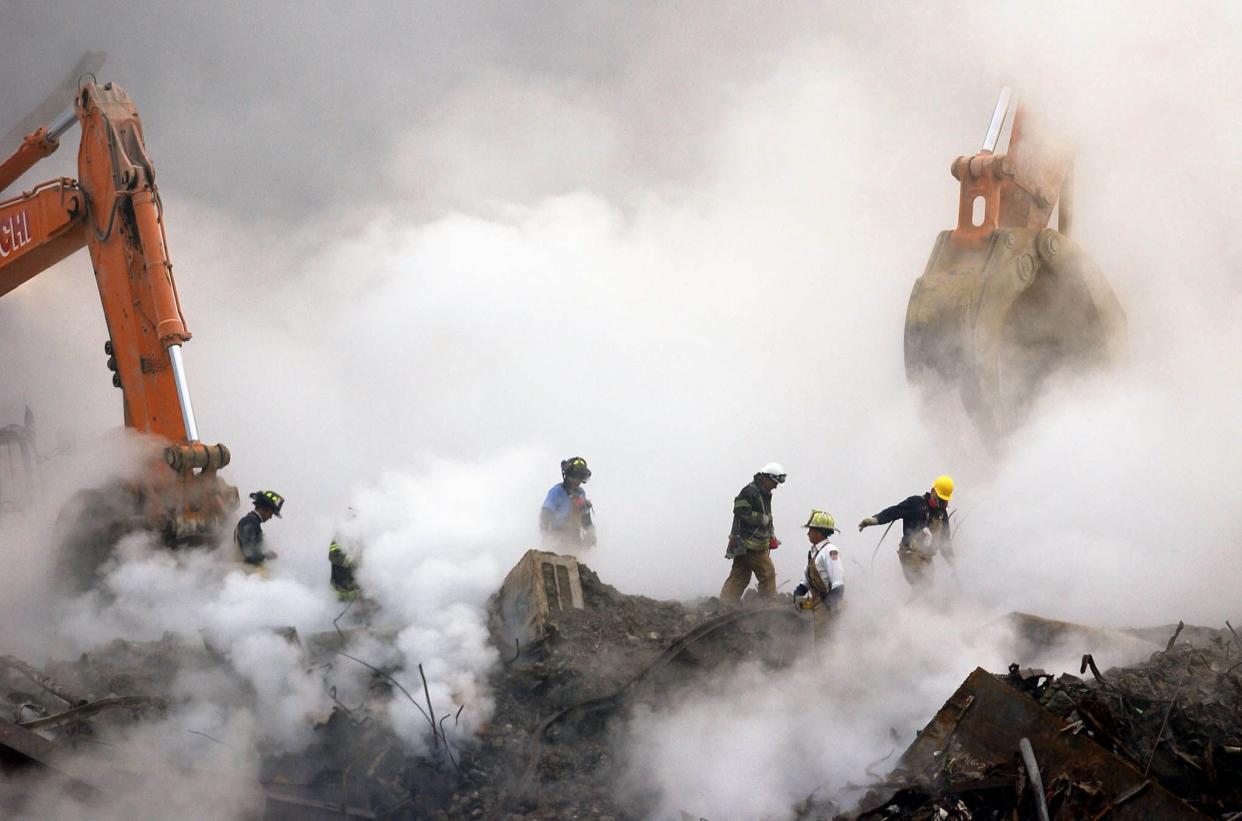 Firefighters make their way over the ruins of the World Trade Center through clouds of dust and smoke at Ground Zero in lower Manhattan, New York on Oct. 11, 2001.