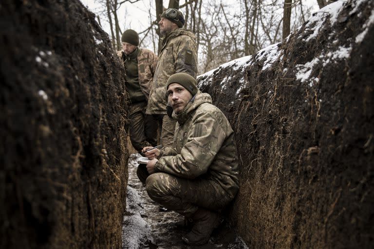 Los soldados de las fuerzas armadas ucranianas se refugian en una trinchera mientras sus compañeros disparan un obús contra las posiciones rusas, en el Donbass