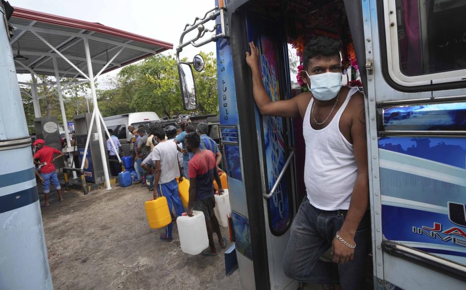 A Sri Lankan bus worker and others wait to buy fuel at a fuel pump in Colombo, Sri Lanka, Wednesday, March 2, 2022. Authorities in Sri Lanka are imposing rolling power cuts across the island nation as its deepening financial crisis leads to shortages of fuel and handicaps its power grid. A currency crunch has hindered imports of fuel and other essentials from overseas, including milk powder, cooking gas, and petrol. (AP Photo/Eranga Jayawardena)