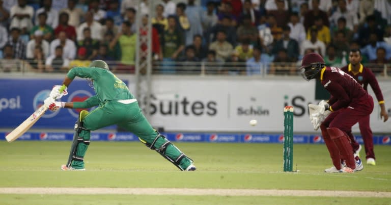 Pakistan's batsman Sarfraz Ahmed (L) hits the ball as West Indies' wicketkeeper Andre Fletcher (L) fields during their second T20I match at the Dubai International Cricket Stadium on September 24, 2016