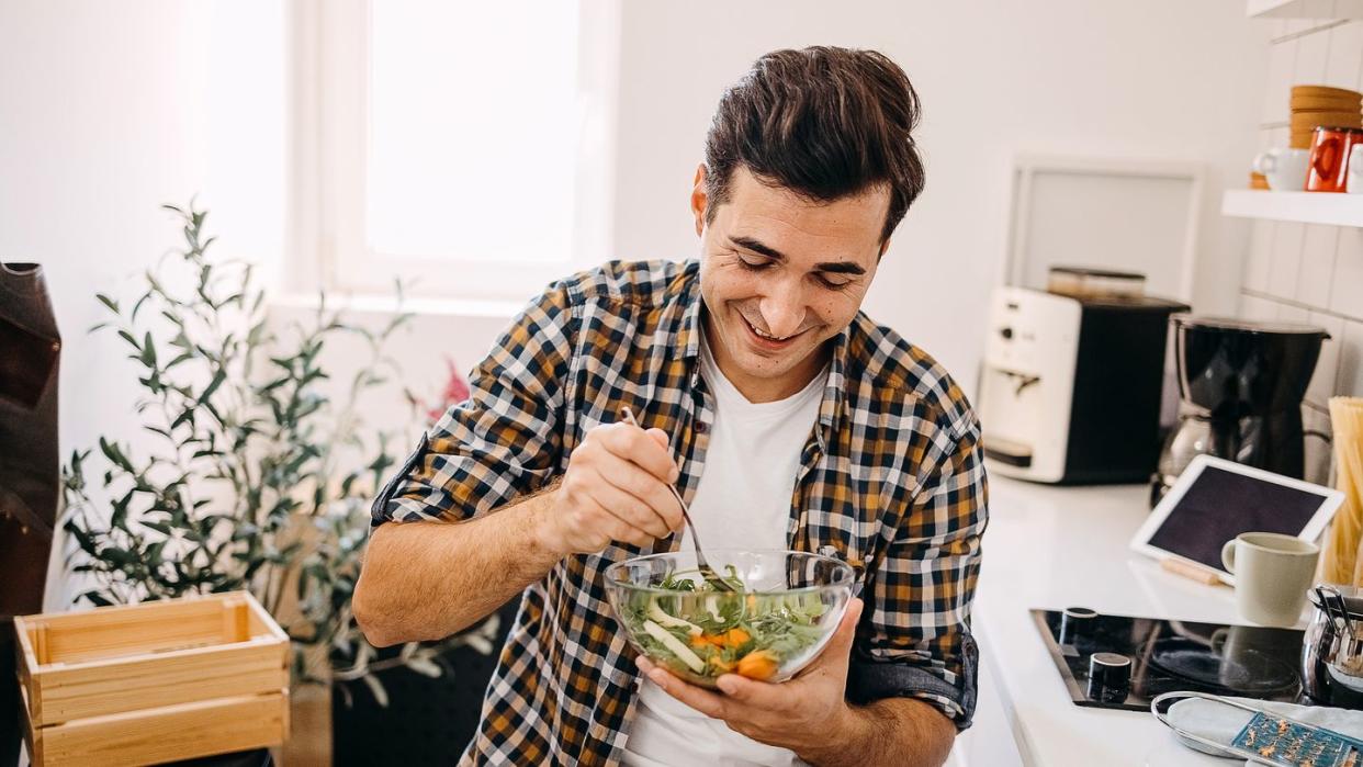 young man eating a salad at home