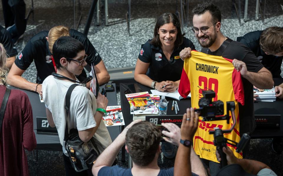 Bryan Cooney, 25, of Detroit, holds a Jamie Chadwick jersey as he takes a photo beside her inside the GM Renaissance Center's Wintergarden for the NTT IndyCar Series driver autograph session in Detroit on Friday, June 2, 2023.