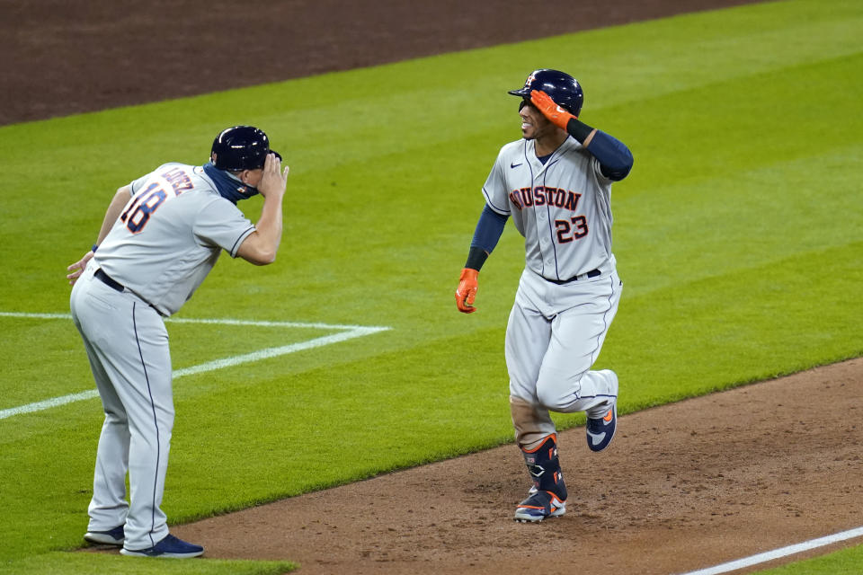 Houston Astros' Michael Brantley (23) shares a salute with third base coach Omar Lopez as Brantley heads toward home after hitting a solo home run against the Seattle Mariners during the sixth inning of a baseball game Tuesday, Sept. 22, 2020, in Seattle. (AP Photo/Elaine Thompson)