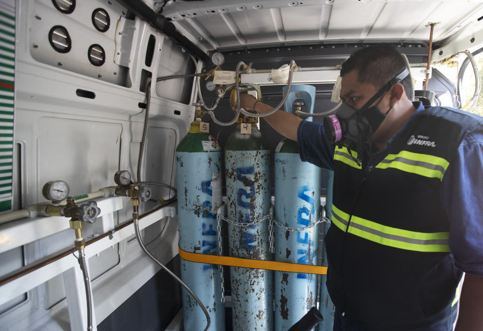 Health worker Jose Antonio Peña refills oxygen tanks for patients with COVID-19 in the Iztapalapa district of Mexico City, Tuesday, Jan. 26, 2021. The city is offering free oxygen refills for patients with COVID-19. (AP Photo/Marco Ugarte)