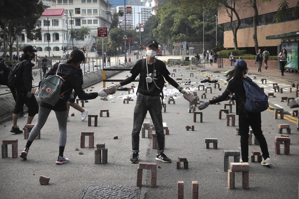 In this Thursday, Nov. 14, 2019, file photo, protesters move bricks as they barricade a road near the Hong Kong Polytechnic University in Hong Kong. Protesters who barricaded themselves inside Hong Kong’s universities have tried to turn the campuses into armed camps, resorting to medieval weapons to stop police from entering the grounds. Their weapons include bows and arrows, catapults and hundreds of gasoline bombs stacked up to ramparts - often built by the students. (AP Photo/Kin Cheung, File)