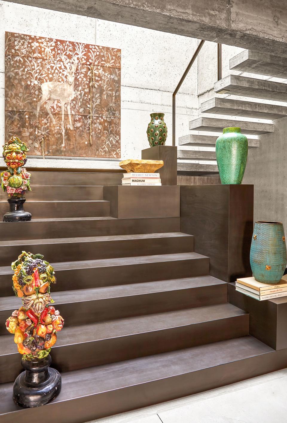 Vintage vases and Giuseppe Arcimboldo–inspired ceramic busts line a black iron stairway.