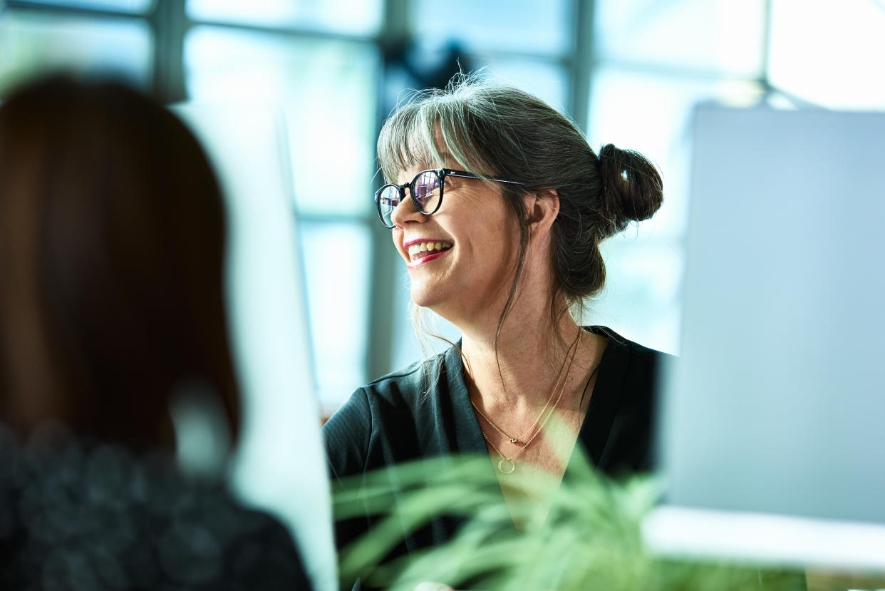 Female office worker in her 50s smiling and looking away, cheerful expression, carefree, relaxed