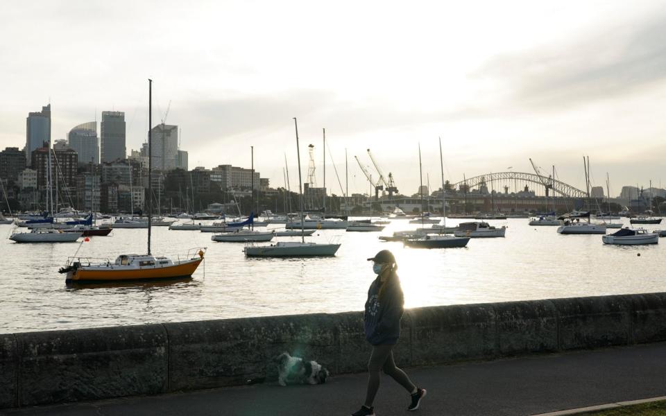 A woman wearing a protective face mask walks along a waterfront path during a lockdown to curb the spread of a coronavirus disease (COVID-19) outbreak in Sydney, Australia, J - Reuters