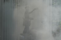 A statue of a postman is enveloped in smoke in front of the Manila Central Post Office as it caught fire early Monday, May 22, 2023 in Manila, Philippines. A massive fire tore through Manila's historic post office building overnight, police and postal officials said Monday. (AP Photo/Aaron Favila)