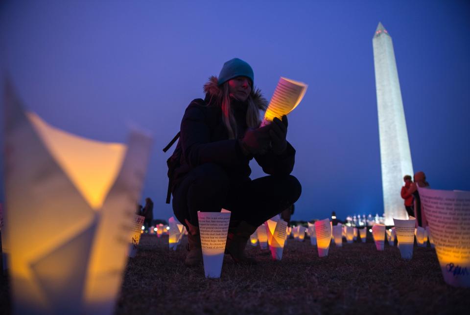 A woman reads messages on paper cones with electric candles in them at the Washington Monument during a protest against Trump in Washington, D.C., on Feb. 3, 2017.