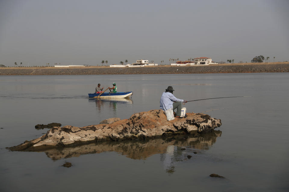 Un hombre pesca en una roca donde es visible el nivel de agua históricamente bajo del Río Paraguay cerca del puente Remanso en Mariano Roque Alonso, Paraguay, el miércoles de octubre de 2020. (AP Foto/Jorge Saenz)