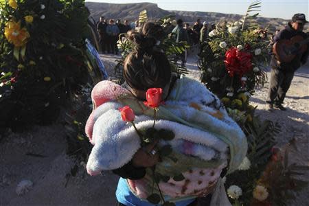 A woman holds roses during the funeral of Idaly Jauche Laguna in Ciudad Juarez December 27, 2013. REUTERS/Jose Luis Gonzalez