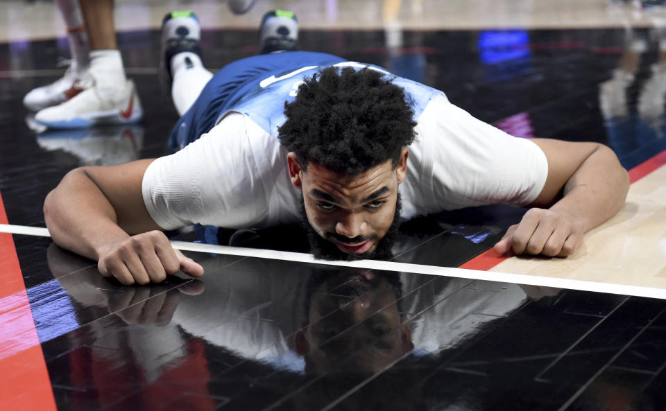 Minnesota Timberwolves center Karl-Anthony Towns lies on the court after being called for an offensive foul during the first half of the team's NBA basketball game against the Portland Trail Blazers in Portland, Ore., Tuesday Feb. 13, 2024. (AP Photo/Steve Dykes)