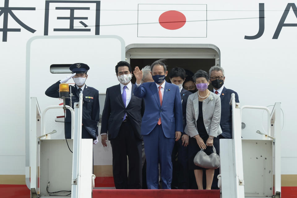 In this photo released by Indonesian Presidential Palace, Japanese Prime Minister Yoshihide Suga, center, waves, accompanied by his wife Mariko Suga, left in foreground, upon arrival at Halim Perdanakusuma Airport in Jakarta, Indonesia, Tuesday, Oct. 20, 2020. Suga arrived in Indonesia on the second leg of his first overseas trip as premier to underscore his government’s aims of countering China in the region (Indonesian Presidential Palace via AP)