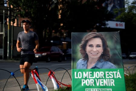 A man runs in front of a campaign signs for Sandra Torres, presidential candidate for the National Unity of Hope (UNE), ahead of the second round run-off vote, in Guatemala City