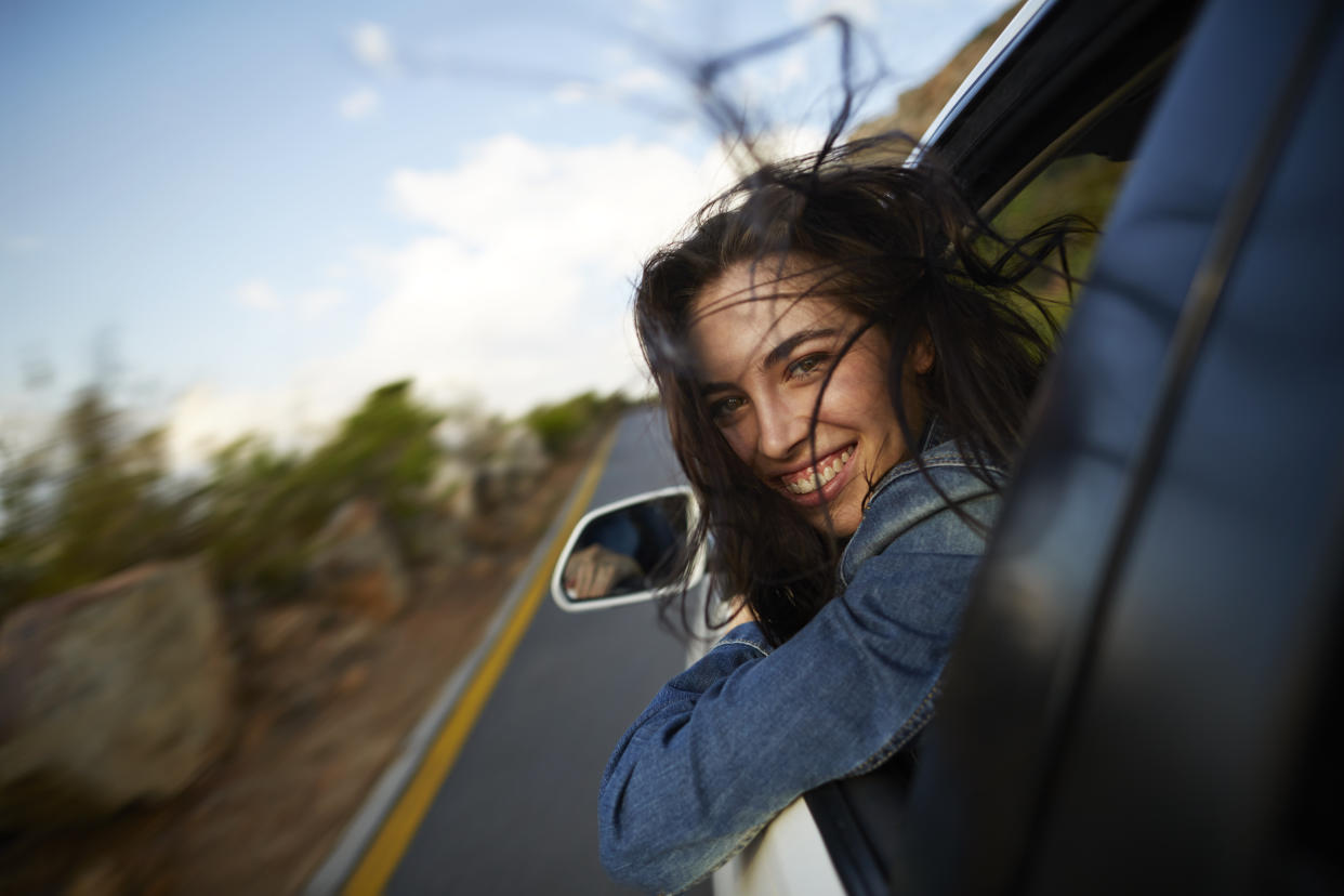 Woman looking outside of car smiling while driving.