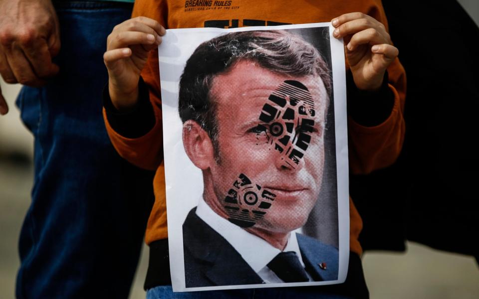 A child holds a photograph of Emmanuel Macron, stamped with a shoe mark, during a protest against France in Istanbul - AP Photo/Emrah Gurel