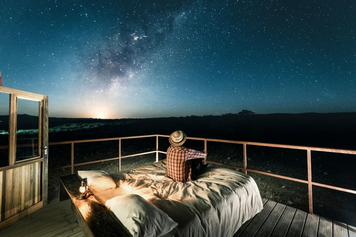 tourist sitting on a bed outdoors under the starry night sky