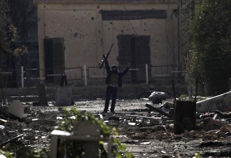 A Free Syrian Army fighter, standing on rubble, gestures as he holds up his weapon in Deir al-Zor, eastern Syria November 21, 2013. REUTERS/Khalil Ashawi