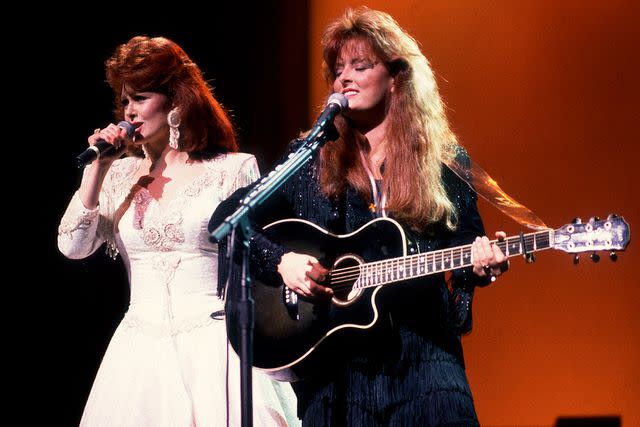 <p>Paul Natkin/Getty</p> Naomi Judd and Wynonna Judd of The Judds performing in Chicago in February 1991