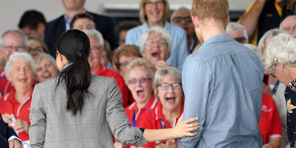 <p>Meghan touches Prince Harry's arm.</p>