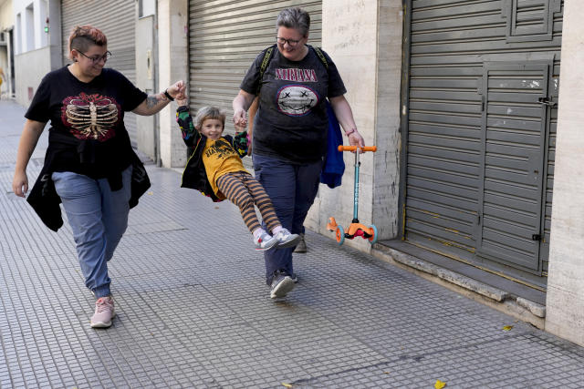 Anastasia Domini, left, and her wife Anna, swing their daughter Una as they walk to a park in Buenos Aires, Argentina, Saturday, April 22, 2023. The same-sex couple are part of an increasing number of Russians from the LGBTQ+ community who left their homeland to escape discrimination and settled in Argentina, where same-sex marriage has been legal for more than a decade. (AP Photo/Natacha Pisarenko)