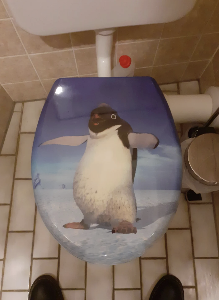 Toilet with a seat cover featuring a standing penguin