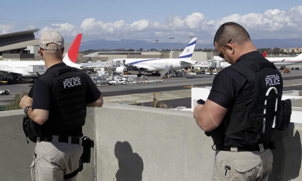 Departement of Homeland Security police officers keep an eye on planes at the Los Angeles International Airport Wednesday, Oct. 10, 2012. In an age when travelers have to toss bottled water at airport security checkpoints, what may be most striking about the arrest of a passenger from Japan wearing a bulletproof vest and flying with checked luggage loaded with a cache of weapons, shackles and body bags is that most of it wasn't illegal on the flight to the U.S. (AP Photo/Damian Dovarganes)