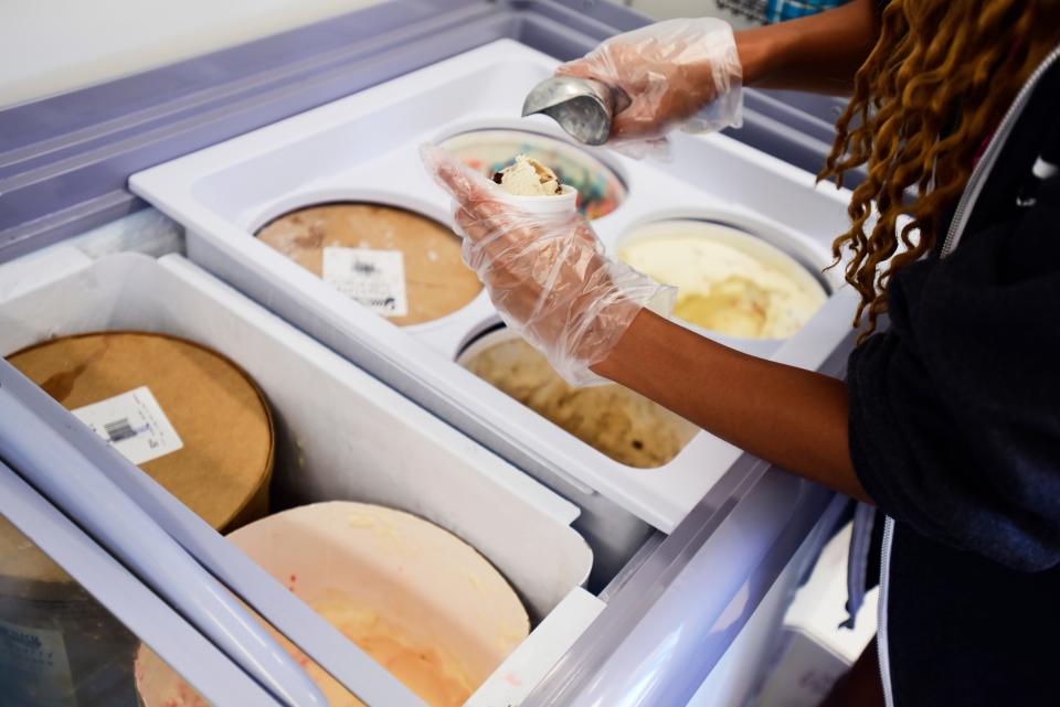 Here's The Scoop employee Makayla Rice scoops a serving of ice cream for a customer outside the new ice cream truck parked on the waterfront along Thomas Edison Parkway on Friday, July 29, 2022.