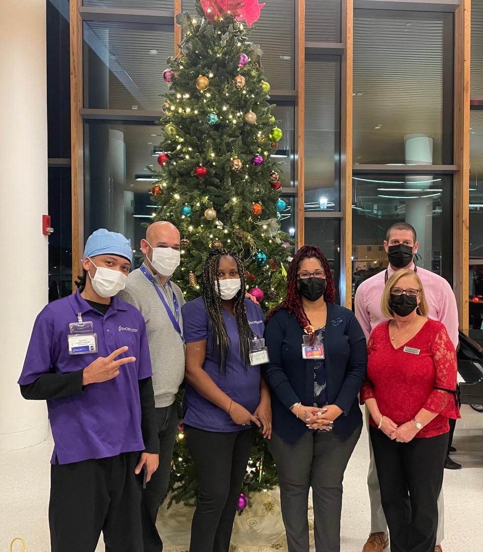 The Auxiliary of Shore Medical Center hosted its annual Tree of Lights Ceremony on Dec. 1. Brenda Martello is joined by members of Shore’s environmental services team in the lighting of the tree. This year, the Auxiliary honored the environmental services team at Shore for their hard work and dedication to keeping the hospital clean and safe, especially throughout the pandemic. Pictured, from left, at the event are Victory Valentine, Carmelo Ortiz, Marie Jeanty, Benita Vandervort, Brenda Martello and Joe Hutcherson.