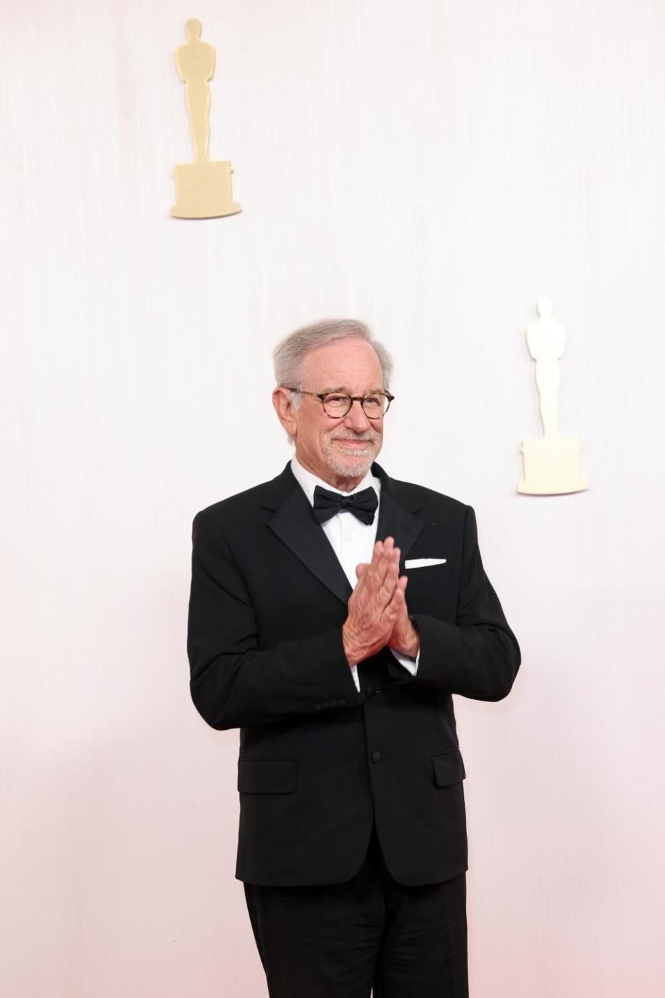Steven Spielberg in a tuxedo, clasping his hands in prayer position
