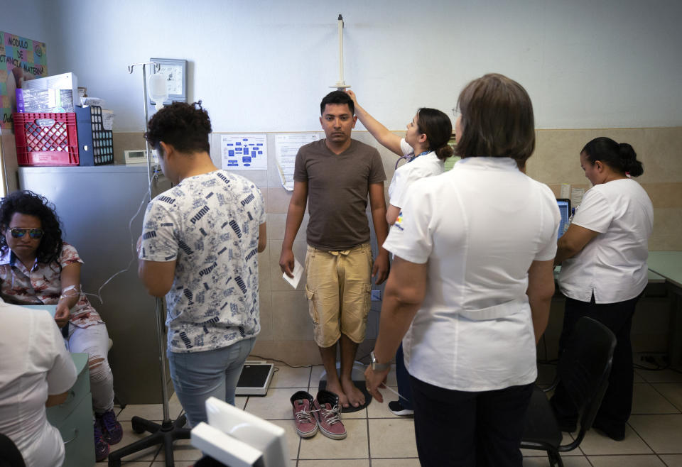 In this July 25, 2019, photo, Samuel, of Honduras, center, is treated at a clinic after taking a bus from El Buen Pastor shelter for migrants in Cuidad Juarez, Mexico. (AP Photo/Gregory Bull)