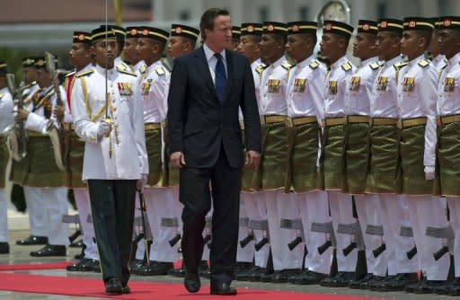 Britain's Prime Minister David Cameron (C) inspects a guard of honour during an official welcoming ceremony in Putrajaya, Malaysia's administrative capital outside Kuala Lumpur. Cameron has called on the international community to "get behind" burgeoning reforms in Myanmar during his Asia tour