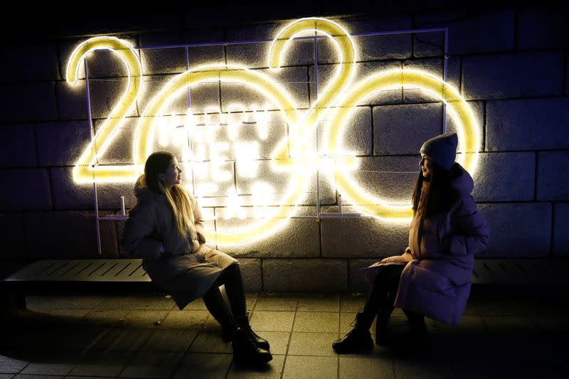 Women pose for a picture in front of a 2020 luminous sign during New Year’s Eve in Seoul