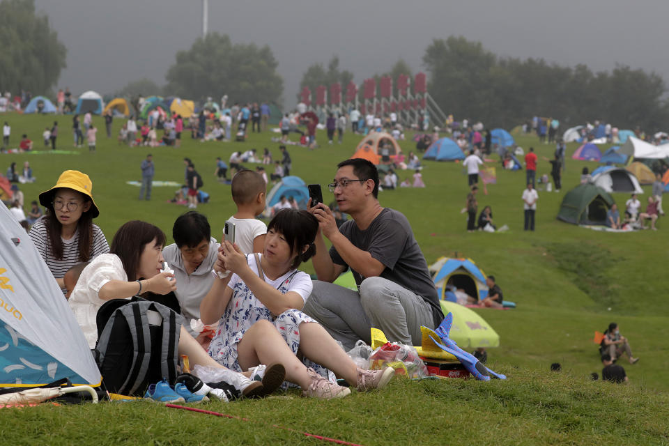 People take smartphones photos as people set camps on a scenic mountain in Yanqing, outskirt of Beijing on Sunday, Aug. 30, 2020. China currently has more than 200 people being treated in hospital for COVID-19, with another more than 300 in isolation after testing positive for the virus without displaying symptoms. (AP Photo/Andy Wong)