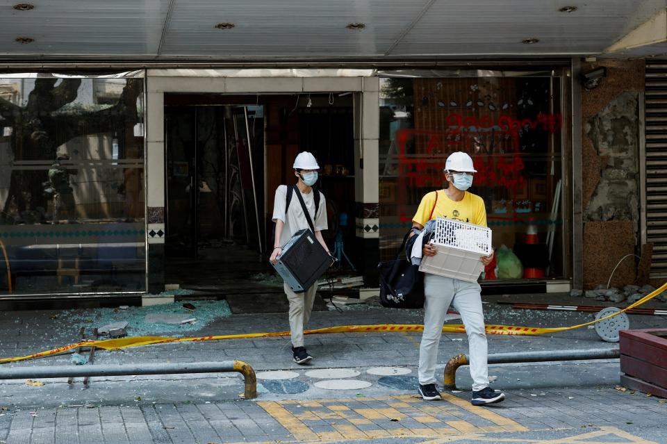 Residents carrying their belongings walk out of a damaged building after entering it in small groups to collect their belongings (REUTERS)