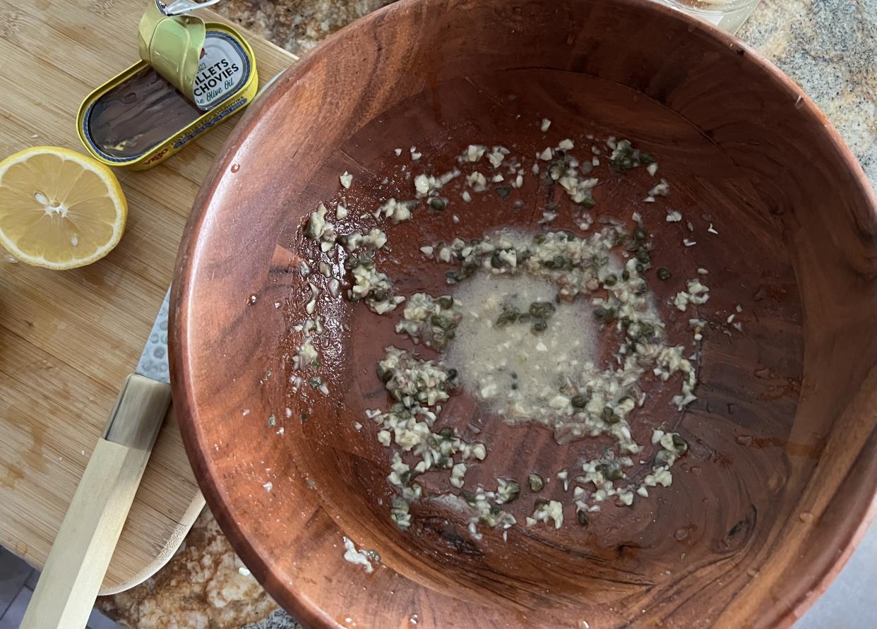 To get the Caesar salad party started, mash anchovies, garlic and capers in a wooden salad bowl with dry mustard powder. (Photo: Terri Peters/Yahoo)