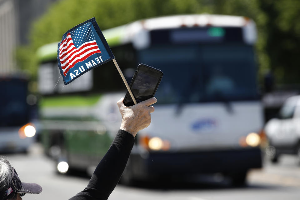 FILE - In this May 13, 2020, file photo, tour guide Barbara Western waves a flag in support of bus and motor coach operators as they circle the National Mall in Washington. As a candidate for the White House, President Donald Trump once said he wanted “whatever is best” for the residents of the nation’s capital. But over the course of his more than three years in office a disconnect between the president and District of Columbia has emerged -- a chasm that has only grown during the coronavirus pandemic. (AP Photo/Patrick Semansky, File)