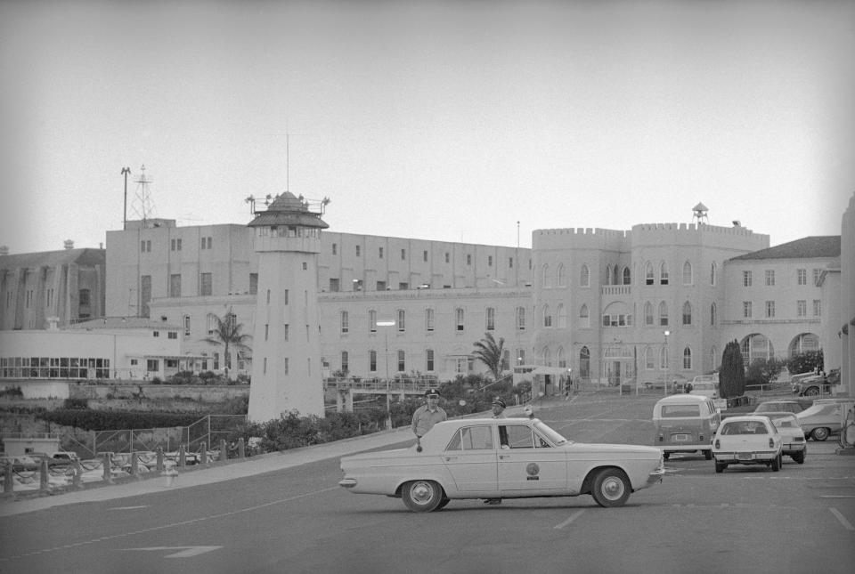 FILE - Two law enforcement officers stand watch outside California's San Quentin prison following an escape attempt, Aug. 21, 1971. The infamous state prison on San Francisco Bay that has been home to the largest death row population in the United States will be transformed into a lockup where less-dangerous prisoners will receive education, training and rehabilitation under a new plan from California Gov. Gavin Newsom. (AP Photo/Ott, File)